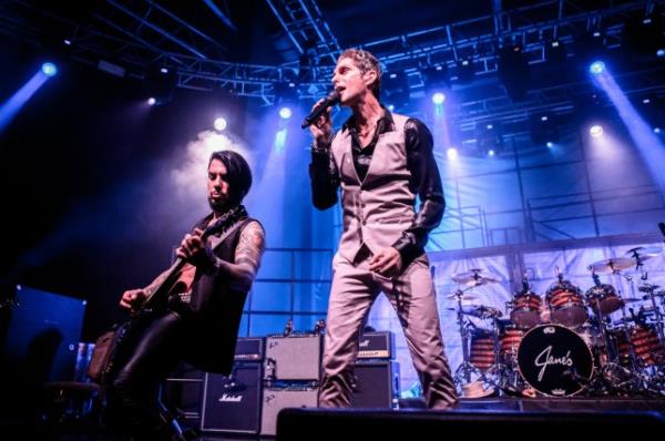 Perry Farrell and Dave Navarro of American rock band Jane's Addiction performing onstage. Perry is singing into a microphone while Dave is playing guitar