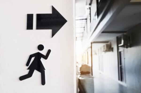 Sign of woman running to the toilet on white cement wall background.