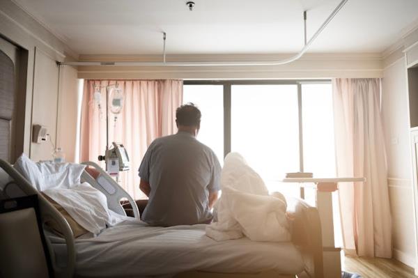 A patient sitting on a hospital bed, seen from behind